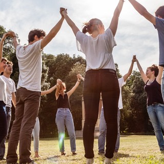 Photo d’un groupe d’employés dehors, les mains levées vers le ciel.